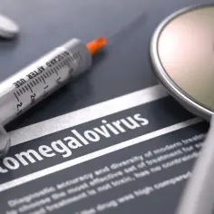Strzykawka i stetoskop na tle dokumentu z napisem "Cytomegalovirus". Może to symbolizować leczenie cytomegalii u noworodka.